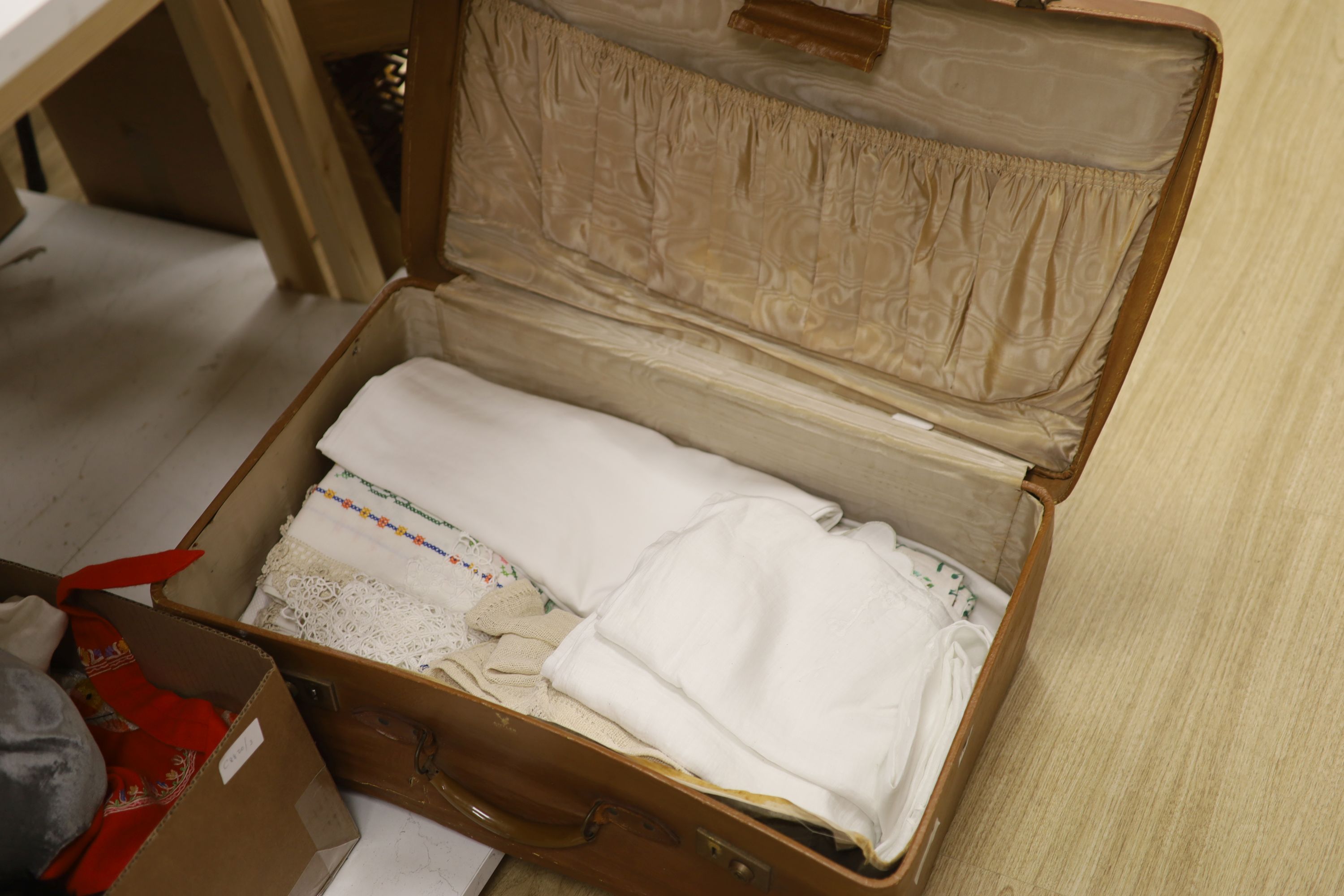 A suitcase of linen table cloths etc